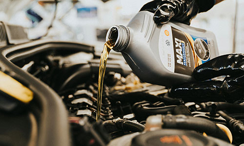 Jemand füllt Öl in den Motor eines Fahrzeugs ein