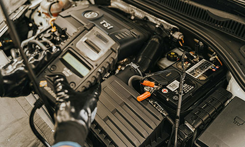 Eine Person arbeitet an einem Auto-Motor und überprüft die Teile.