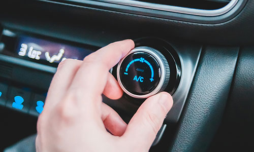 Eine Person justiert die Klimaanlage im Auto.