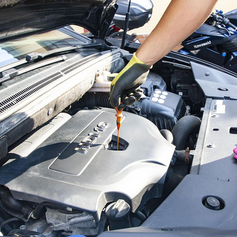 Eine Person giesst Öl in den Motor eines Autos.